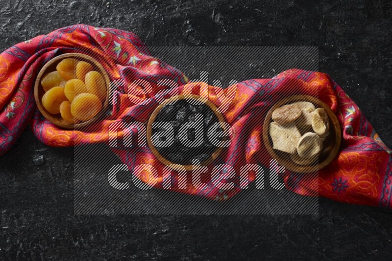 Dried fruits in wooden bowls in a dark setup