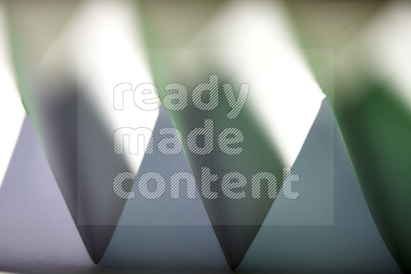 صورة مجردة مقربة تظهر طيات ورقية هندسية حادة بتدرجات اللون الأبيض و الأخضر