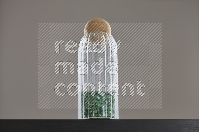 Sequins in a glass jar on black background