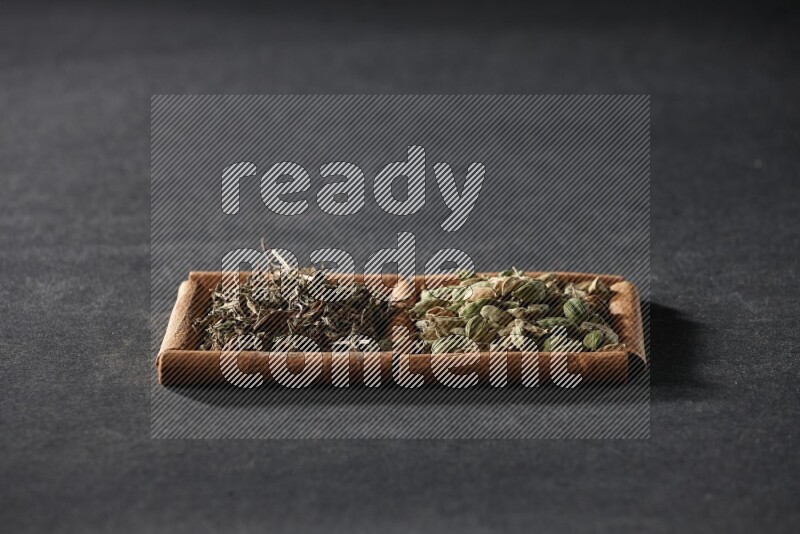 2 squares of cinnamon sticks full of cardamom and dried basil on black flooring