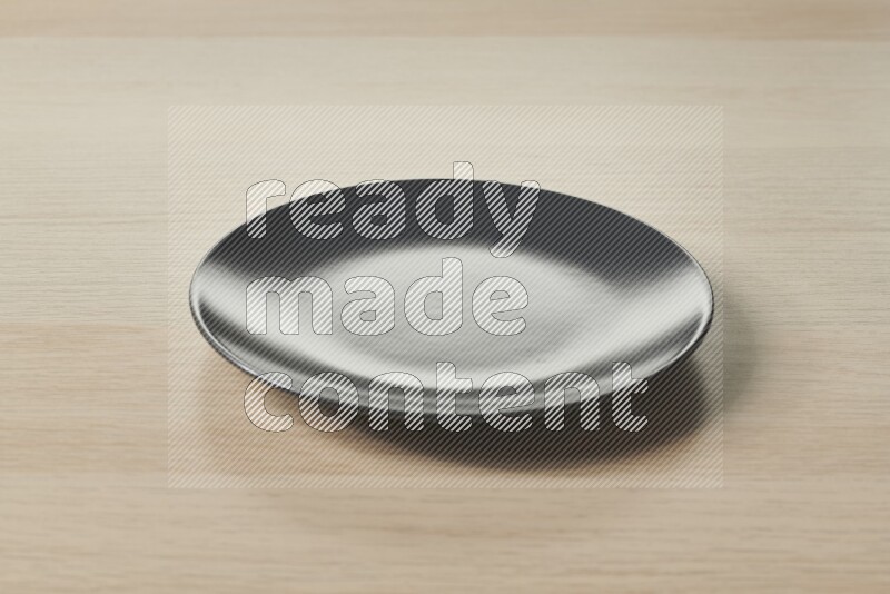 A black ceramic circular plate on light wooden background