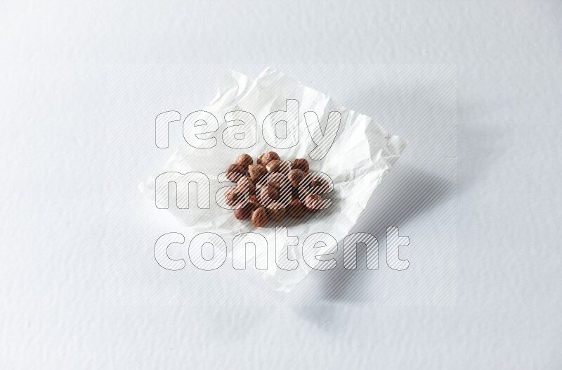 Peeled hazelnuts on a crumpled piece of paper on a white background in different angles