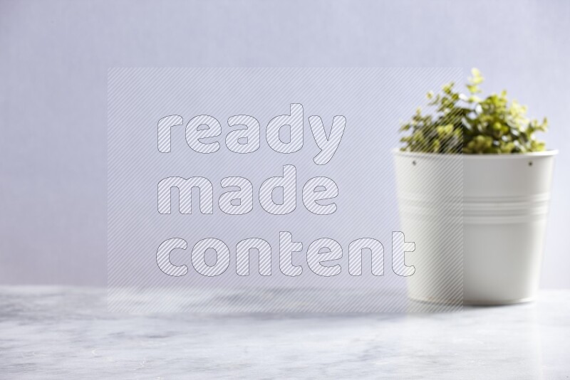 Artificial plant in white pot on grey marble background
