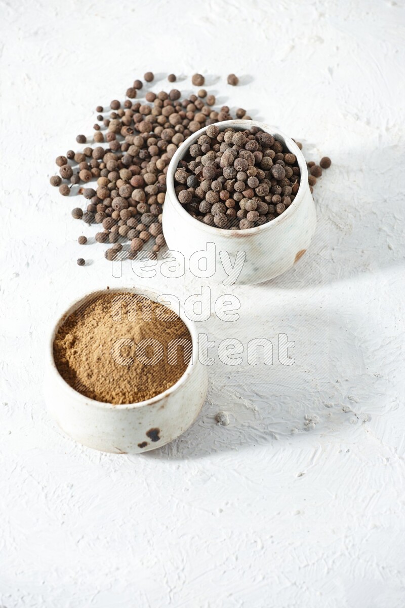 وعاءان بيج، أحدهما ممتلئ ببودرة بهار الفلفل الحلو والآخر بالحبوب مع البودرة والحبوب متناثرة على خلفية بيضاء