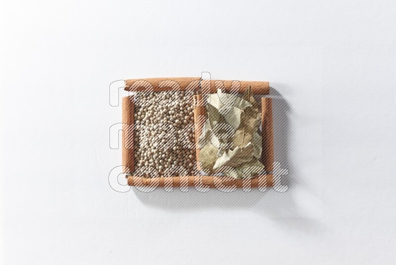 2 squares of cinnamon sticks full of white pepper and bay laurel leaves on white flooring