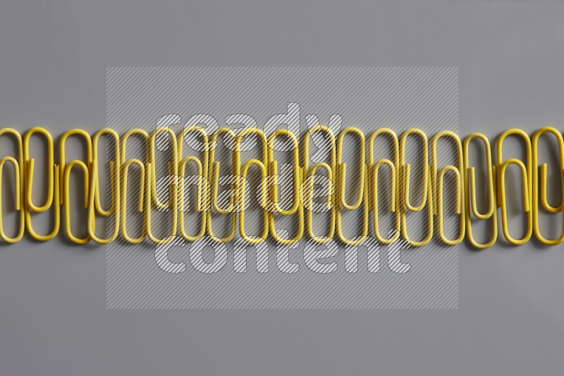 Yellow paper clips isolated on a grey background