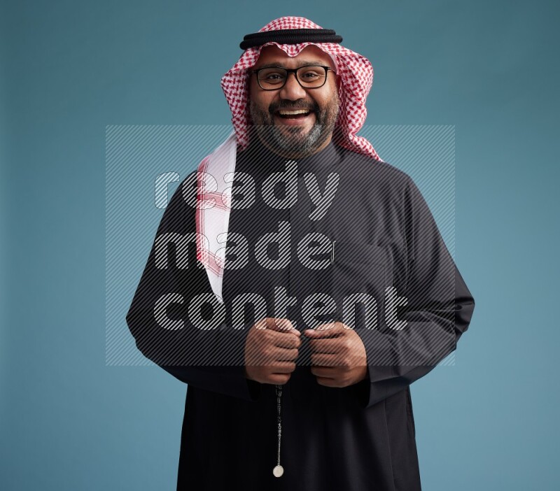 Saudi Man with shimag Standing Interacting with the camera on blue background