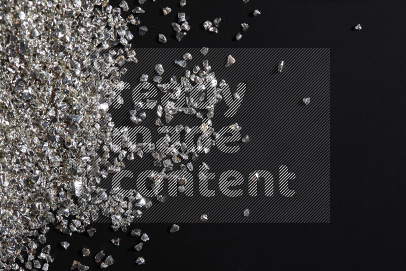 Silver shimmering fragments of glass scattered on a black background