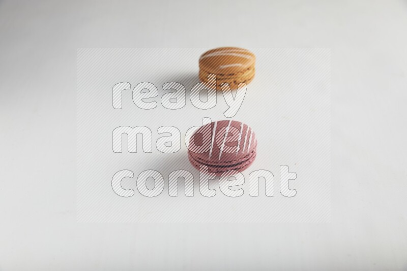 45º Shot of of two assorted Brown Irish Cream, and Red Poppy Flower macarons on white background