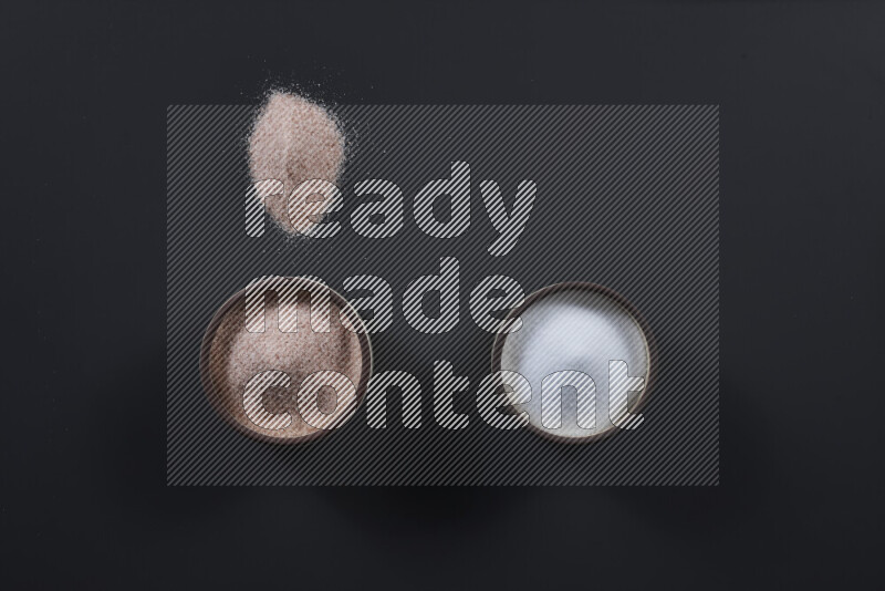 2 pottery bowls one is filled with himalayan salt and the other with white salt on black background