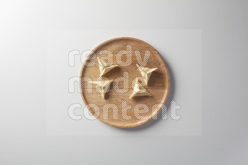 Four Sambosas on a wooden round plate on a white background