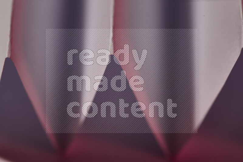 A close-up abstract image showing sharp geometric paper folds in white and pink gradients