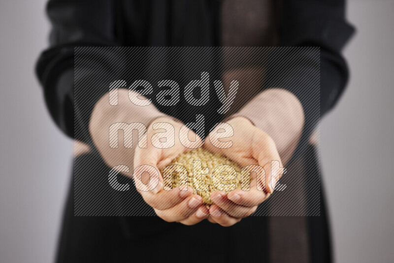 Woman in abaya holding different kinds of legumes in different positions