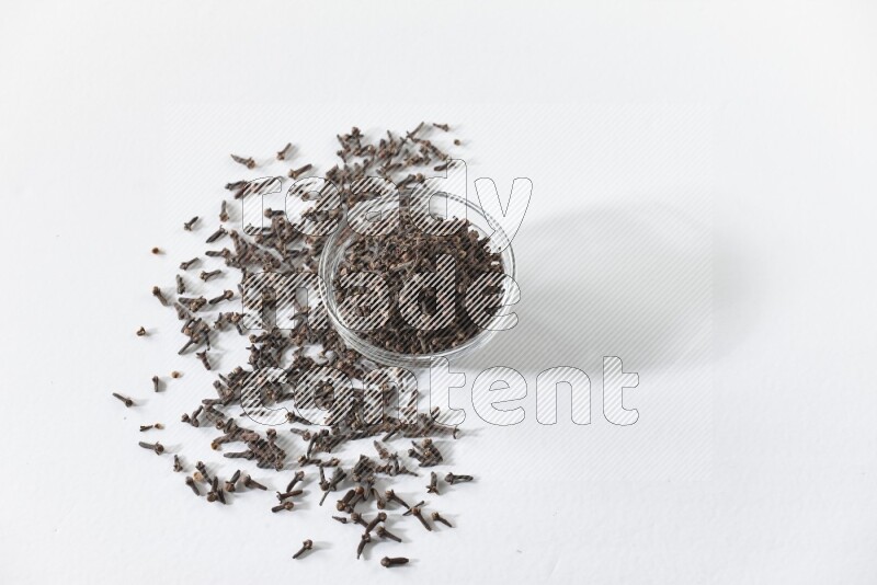A glass bowl full of cloves on a white flooring