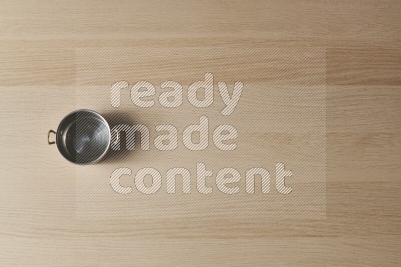 A small copper pot on light wooden background