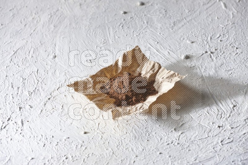Cloves powder on crumpled piece of paper on a textured white flooring