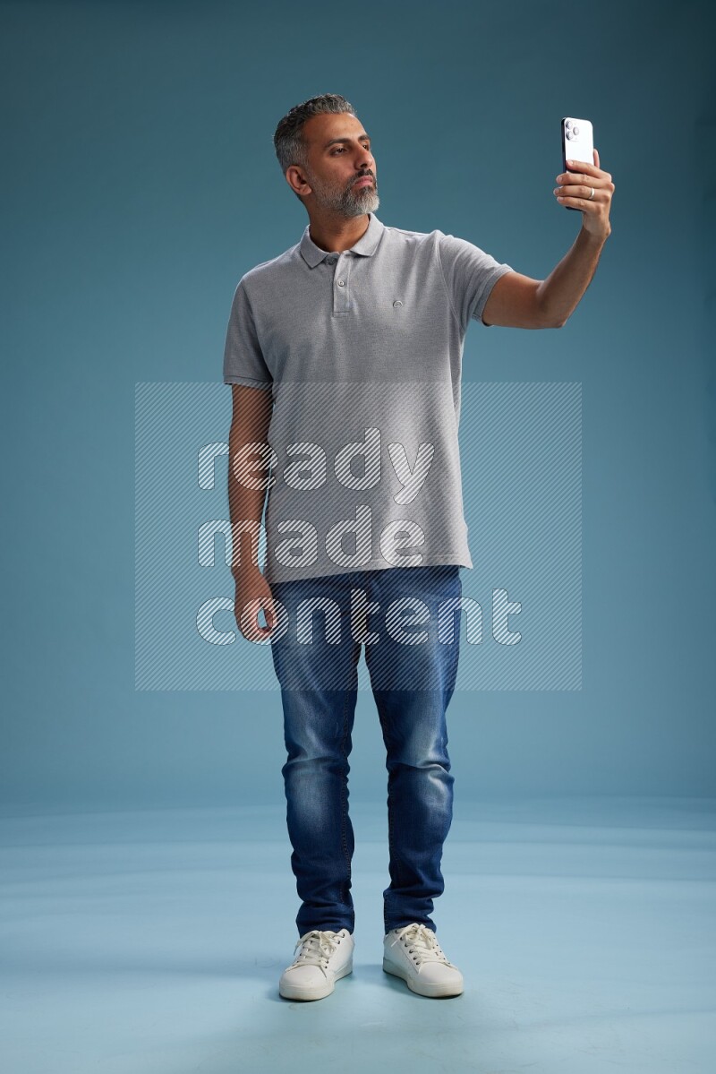 Man Standing taking selfie on blue background