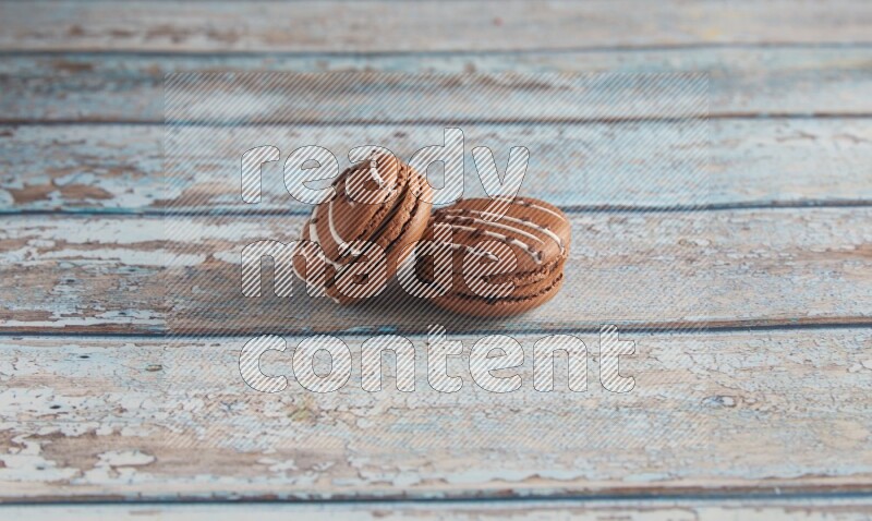 45º Shot of two Brown white  Chocolate Caramel macarons on light blue wooden background