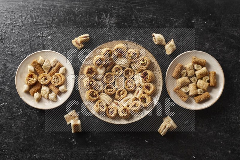 حلويات شرقية في أطباق فخارية علي خلفية سوداء خشبية