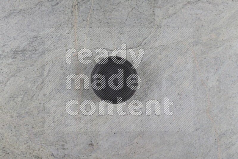 A black pottery bowl on grey marble background