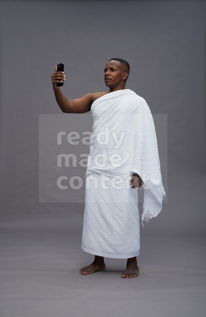 A man wearing Ehram Standing taking selfie on gray background