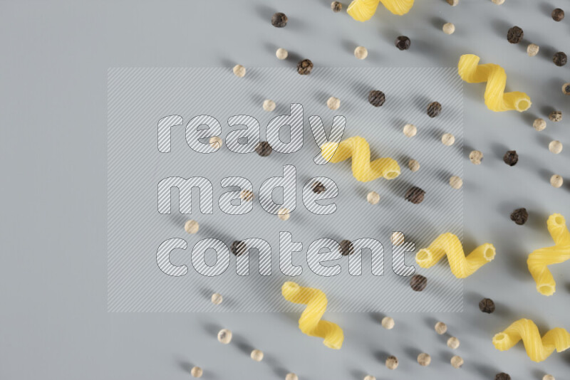 Raw pasta with different ingredients such as cherry tomatoes, garlic, onions, red chilis, black pepper, white pepper, bay laurel leaves, rosemary, cardamom and mushrooms on light blue background