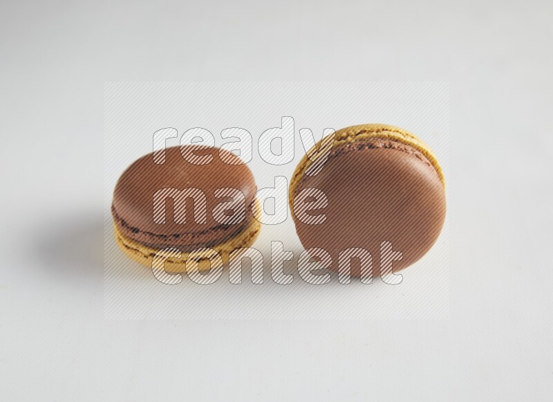 45º Shot of two Yellow and Brown Chai Latte macarons on white background