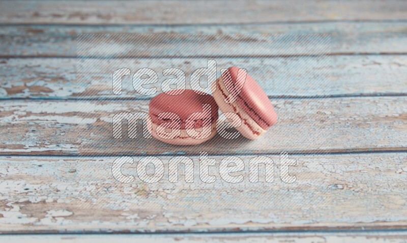 45º Shot of two Pink Litchi Raspberry macarons on light blue wooden background