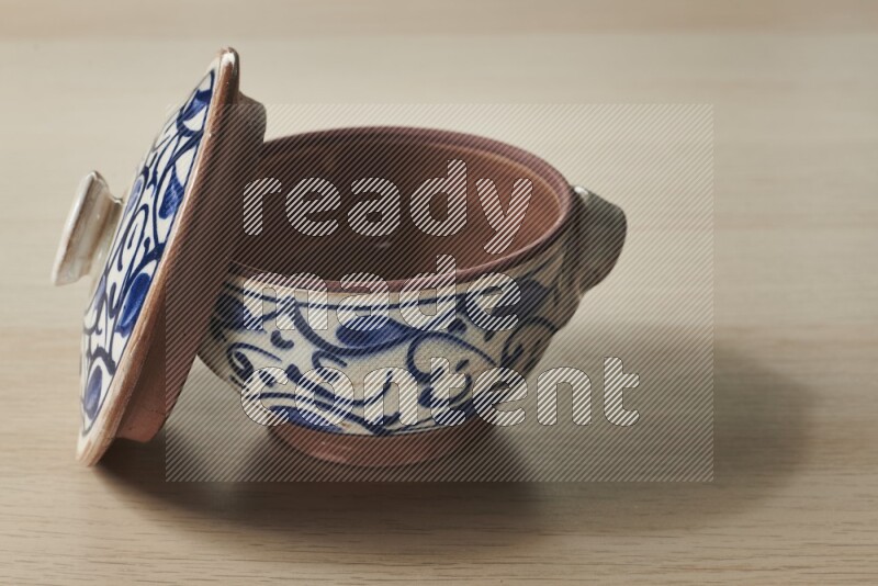 A multicolored pottery pot on light wooden background