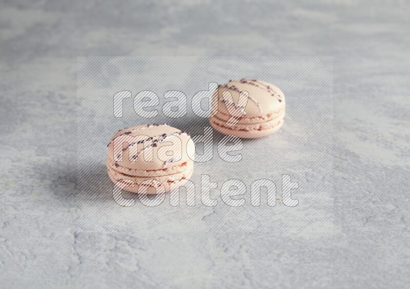 45º Shot of two pink orange blossom macarons  on white  marble background