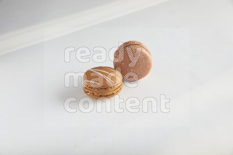 45º Shot of of two assorted Brown Irish Cream, and Brown Hazelnuts macarons on white background