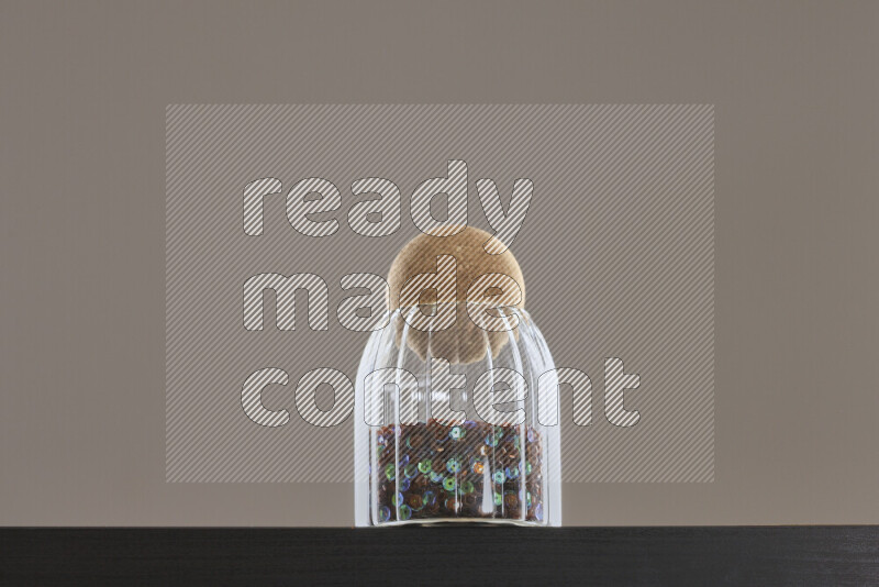 Sequins in a glass jar on black background