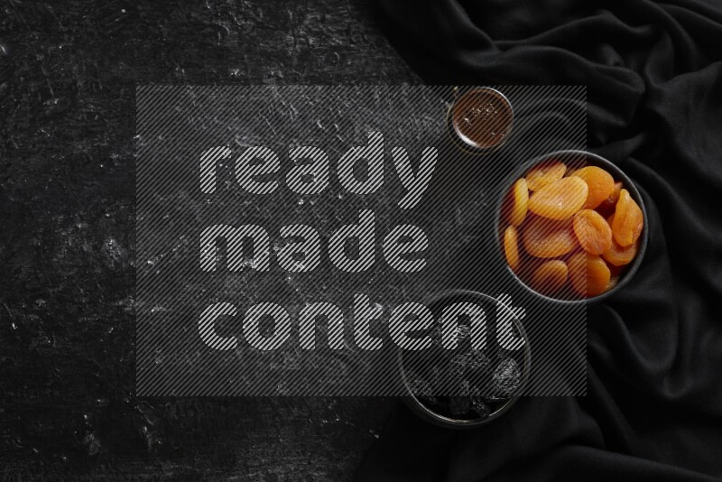 Dried fruits in pottery bowls with coffee in a dark setup