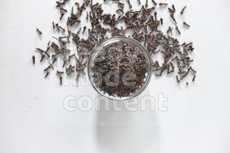 A glass bowl full of cloves on a white flooring