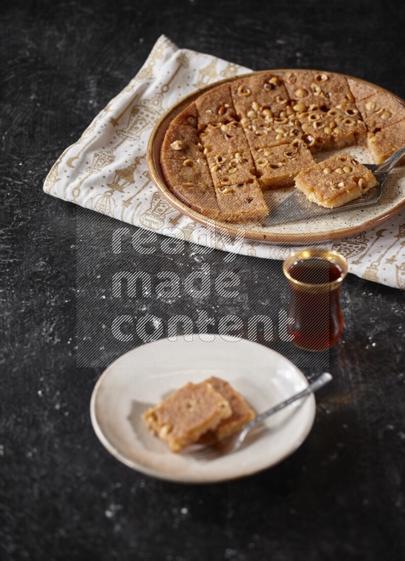 Basbousa with tea in a dark setup