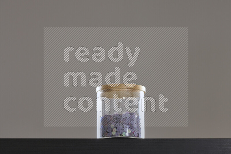 Sequins in a glass jar on black background