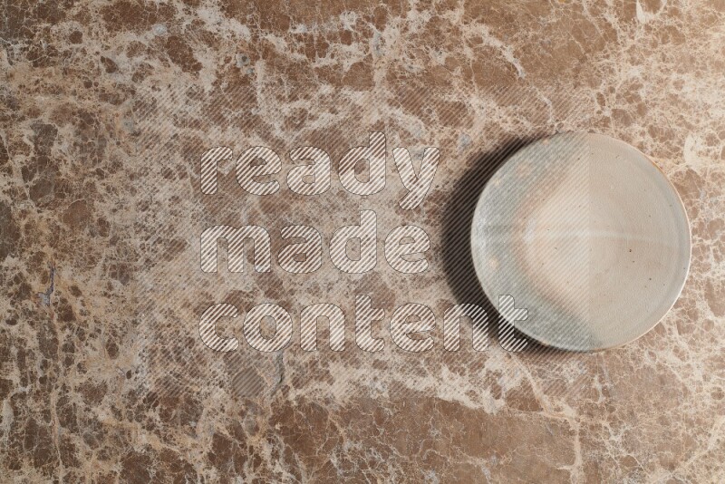 A multicolored pottery plate on beige marble background
