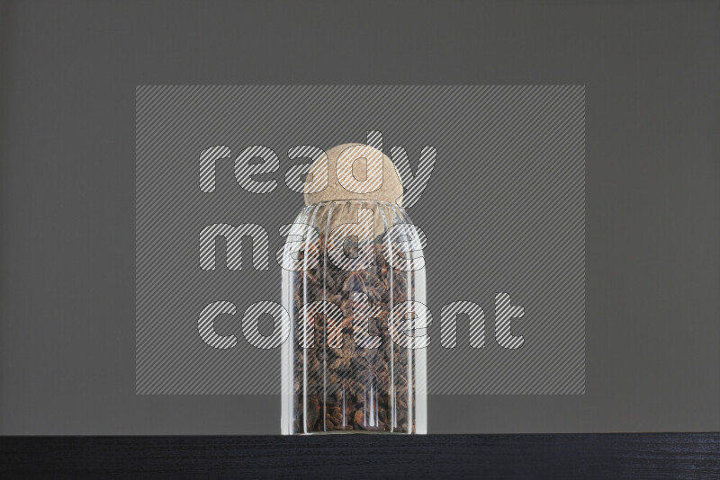 Star anise in a glass jar on black background