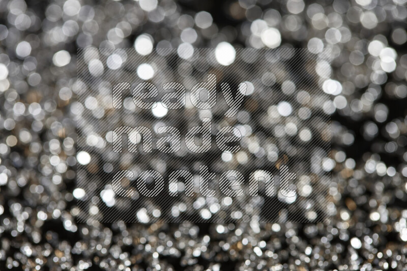 Silver shimmering fragments of glass scattered on a black background