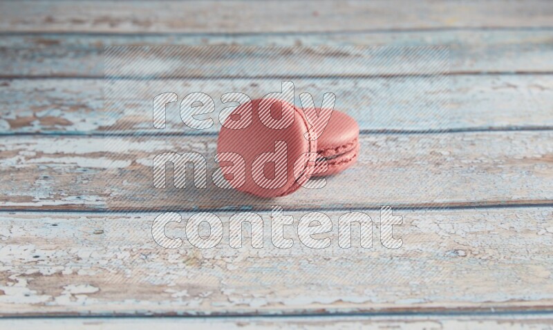 45º Shot of two Pink Raspberry macarons on light blue wooden background