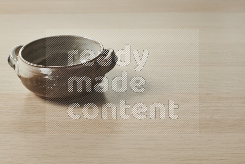 A multicolored pottery bowl on light wooden background