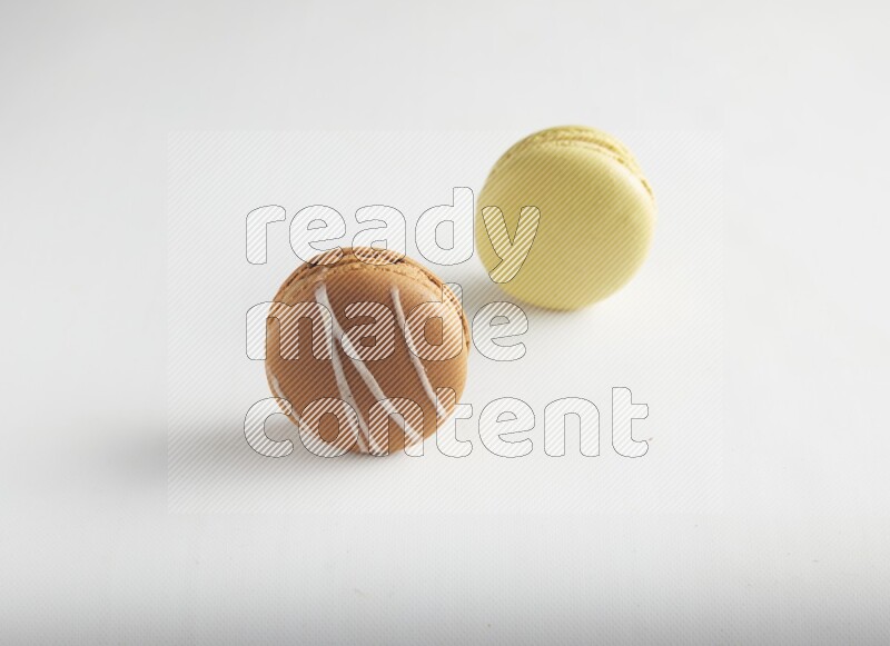 45º Shot of of two assorted Brown Irish Cream, and Yellow Lime macarons on white background