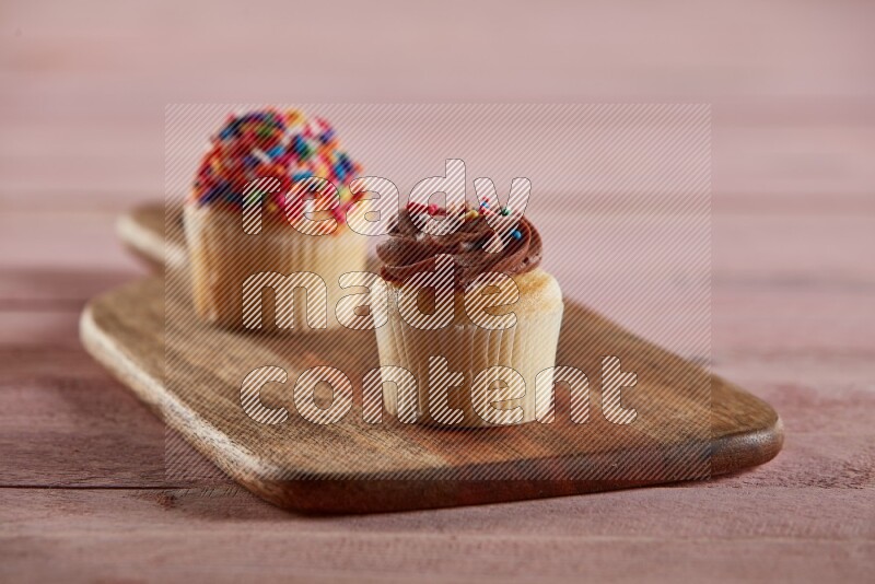 Vanilla mini cupcake topped with chocolate cream on a wooden board