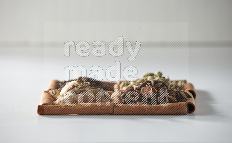 4 squares of cinnamon sticks full of tea, cardamom, star anise and ginger on white flooring