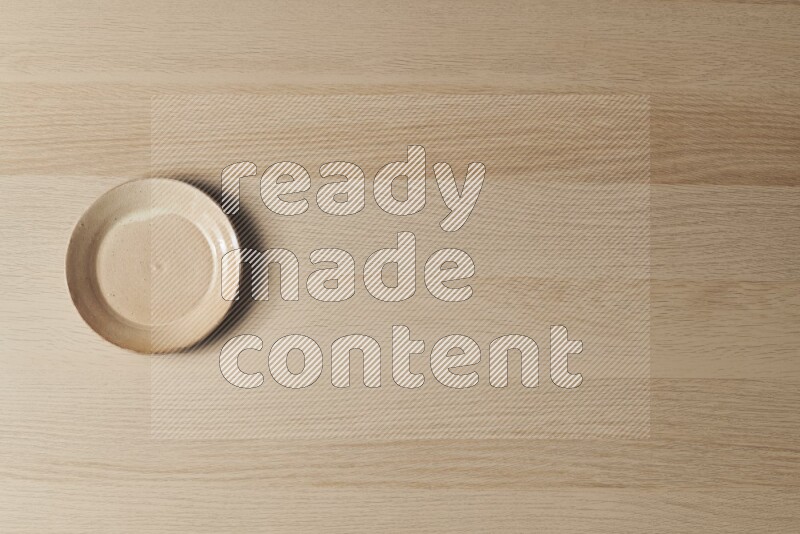 A beige pottery plate on light wooden background