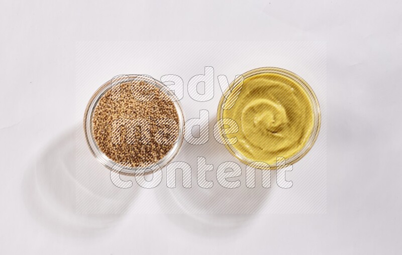 2 glass bowls, one full of mustard seeds and the other full of mustard paste on white flooring