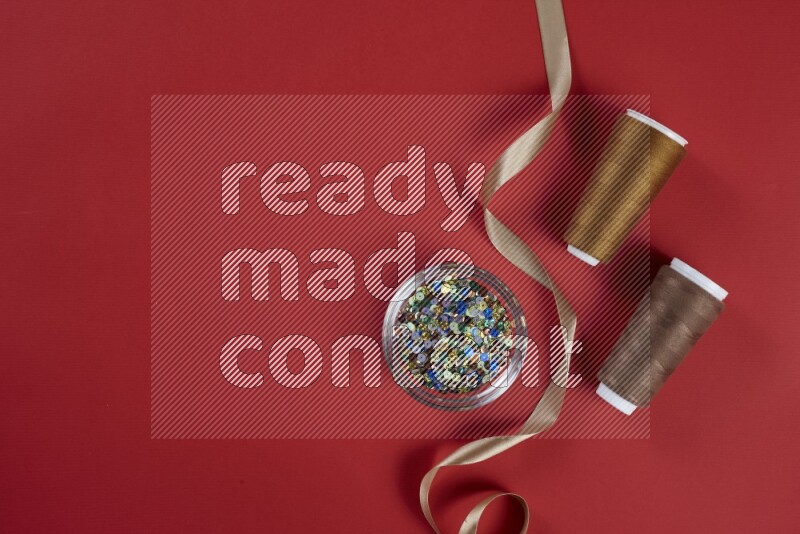 مجموعة من أدوات الخياطة والتفصيل بنية وحمراء اللون على خلفية حمراء