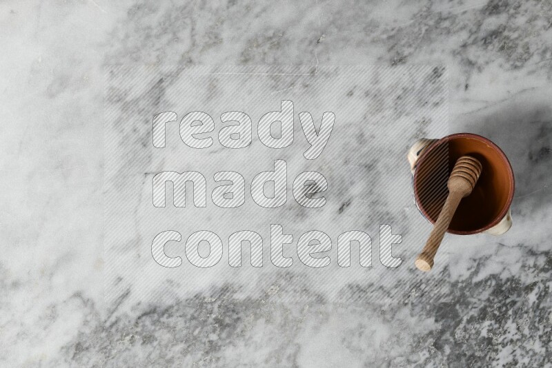 Decorative Pottery Pot with wooden honey handle in it, on grey marble flooring, Top View