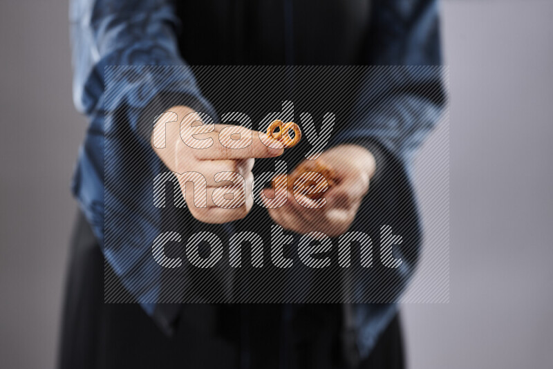 Woman in abaya holding different kinds of snacks in different positions