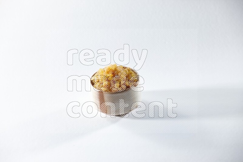 A beige ceramic bowl full of raisins on a white background in different angles
